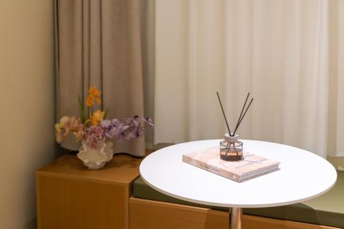 a white table with a book and a vase of flowers at Xiamen Evening Breeze Hotel in Xiamen