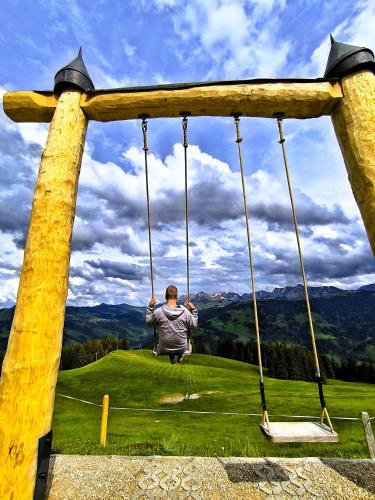 a man is sitting on a swing at Ferienwohnung Kassler - nur 300m vom See in Schwarzsee