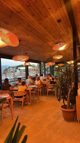 people sitting at tables in a restaurant with lights at Sokakağzı Otel & Beach in Ayvacık