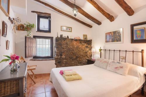 a bedroom with a bed and a stone wall at Casa Rural La Rana Verde in Los Romeros
