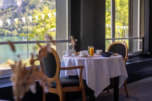 a table with a white table cloth and chairs and a window at Logis Hotel L'Embarcadère in Nantua