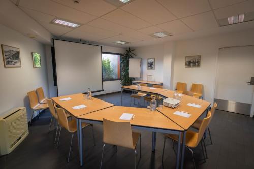 a conference room with tables and chairs and a whiteboard at Logis Hotel L'Embarcadère in Nantua
