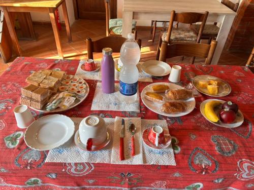 a table with plates of food on a red table cloth at Azzurre BeB in Laterina