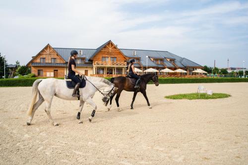 two people riding horses in front of a house at Hotel Rozálka in Pezinok