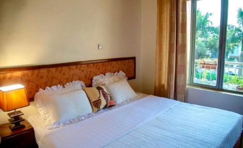 a bedroom with a large white bed with a window at Hotel Greenwich in Kigali