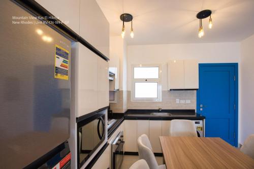 a kitchen with a table and a blue door at Mountain View Luxury Garden Chalet - North Coast in Ras Elhekma