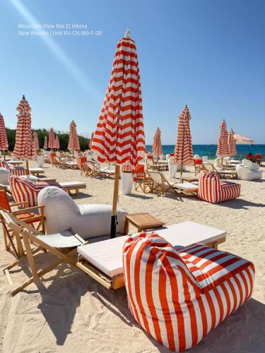 a group of lounge chairs and umbrellas on a beach at Mountain View Luxury Garden Chalet - North Coast in Ras Elhekma