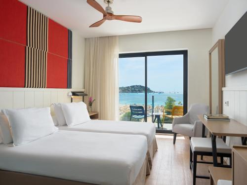 a hotel room with two beds and a view of the ocean at H10 Casa del Mar in Santa Ponsa