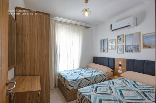 a hotel room with two beds and a window at Mountain View Luxury Garden Chalet - North Coast in Ras Elhekma
