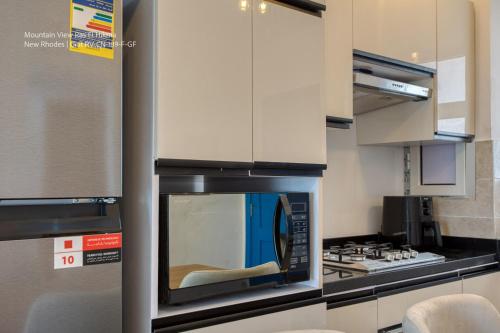a kitchen with a stove and a microwave at Mountain View Luxury Garden Chalet - North Coast in Ras Elhekma