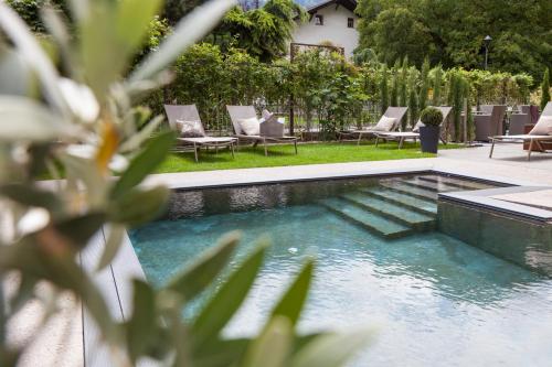 een zwembad in een tuin met stoelen ernaast bij Hotel Stefanshof in Plaus