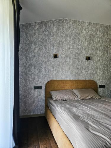 a bedroom with a bed with a gray wall at Hotel resort Sedula in Skogalis