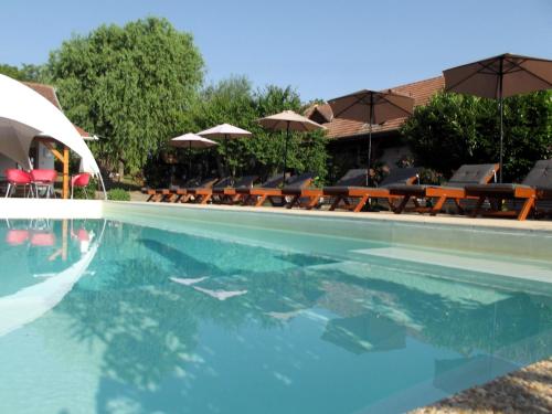 a swimming pool with tables and umbrellas and chairs at Remser Haus in Zalakaros