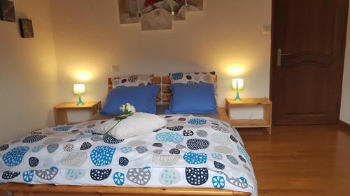 een slaapkamer met een bed met blauwe kussens en twee lampen bij le parc des combes in Saint-Beauzile