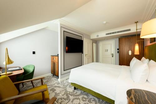 a hotel room with a white bed and a tv at Hotel Saski Krakow Curio Collection by Hilton in Kraków