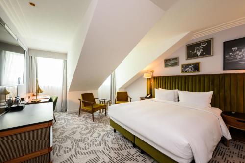 a bedroom with a large white bed and a desk at Hotel Saski Krakow Curio Collection by Hilton in Kraków