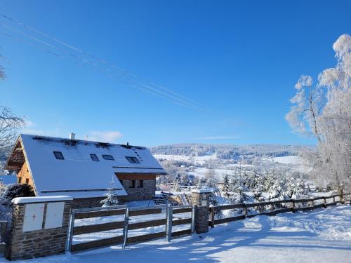 a house in the snow with a fence at Apartmány Stachy Churáňov in Stachy