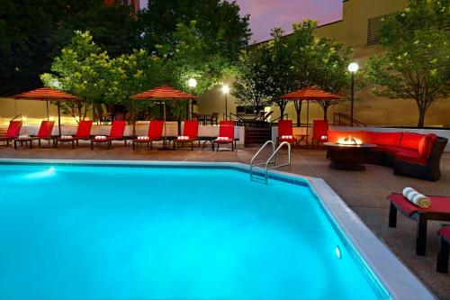 a swimming pool with chairs and tables and umbrellas at Marriott Kansas City Overland Park in Overland Park