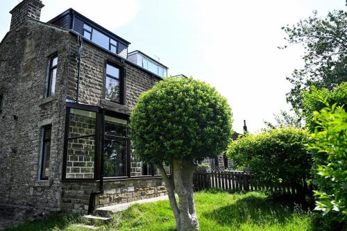 an old stone house with a tree in front of it at Cowpe Lowe View House in Newchurch