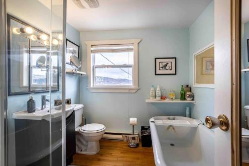 a bathroom with a toilet and a sink and a tub at Iconic Battery Cottagesignal Hillsea&city Views in St. John's