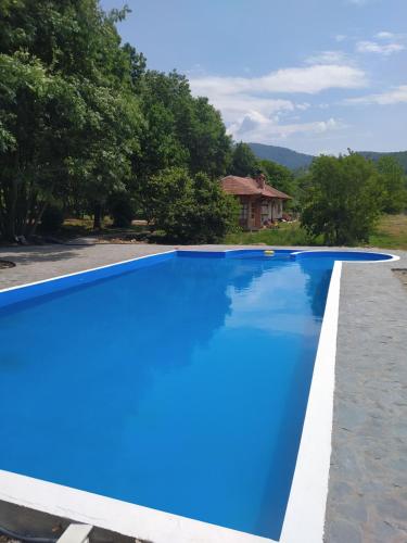a blue swimming pool in front of a house at Vodenica Lug in Strmosten