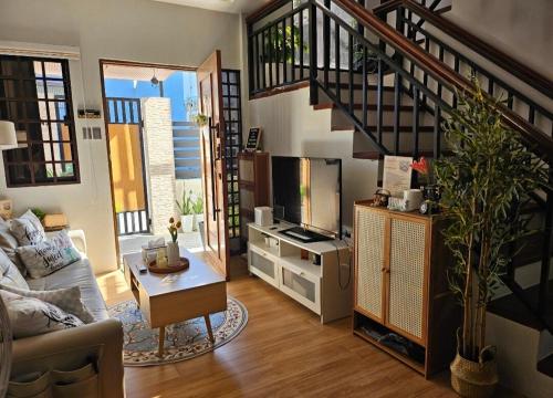 un soggiorno con scala, divano e TV di Casa Corazon - Pineview Heights - Amadeo Tagaytay a Dagatan