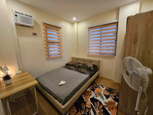 a small bedroom with a bed and a fan at CASA CORAZON Spacious 4BR House Near Tagaytay for Wedding Prep Family Gatherings Reunions and Celebrations Pet Friendly and PWD Accessible in Dagatan