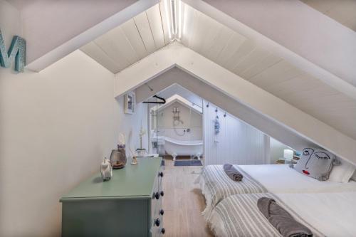a attic bedroom with a bed and a bath tub at Kalk Bay Condo at The Majestic in Kalk Bay