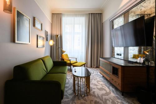 a living room with a green couch and a flat screen tv at Hotel Saski Krakow Curio Collection by Hilton in Kraków