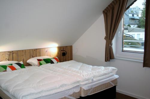 a bedroom with a large white bed with a window at UplandParcs Residence Winterberg in Winterberg