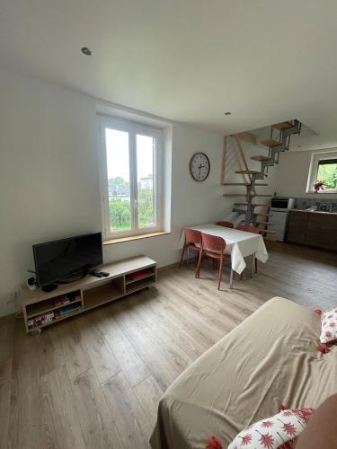 ein Wohnzimmer mit einem Bett, einem TV und einer Treppe in der Unterkunft Bienvenue au petit point de vue in Lisieux