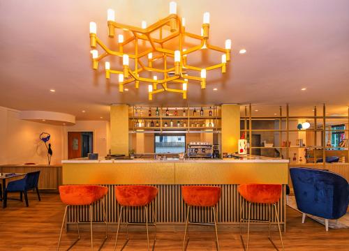 a kitchen with a bar with orange chairs and a chandelier at Hotel Harmony-Smile in Lido di Camaiore