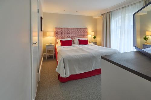 a hotel room with a large bed with red pillows at Elite Hotel Mollberg in Helsingborg