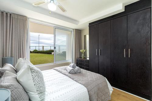 una camera da letto con un letto e una grande finestra di 2 Bedroom Seaview, Holiday Apartment, Lagoon Beach a Città del Capo
