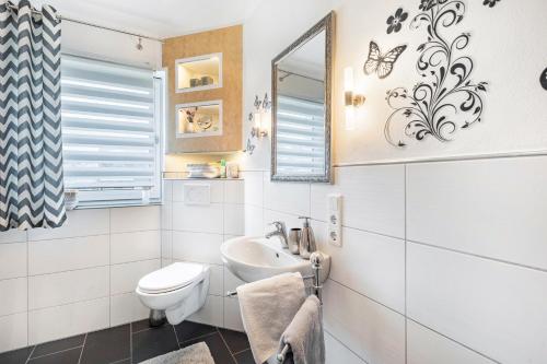 a white bathroom with a toilet and a sink at Ferienwohnung Sonnenblick und Relax in Nieder-Röhre