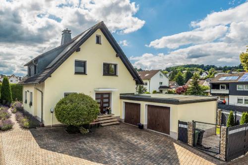 a white house with a black roof and a driveway at Ferienwohnung Sonnenblick und Relax in Nieder-Röhre