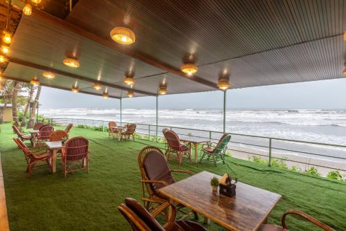 a patio with tables and chairs and the ocean at Amadi Beach Front Resort in Mandrem