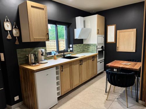 a kitchen with black walls and wooden cabinets and a table at gîte romantique in Etalondes-la-Pipe