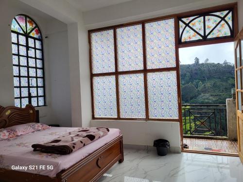a bedroom with a bed and windows with a view at Bison Valley View Stay in Kodaikānāl