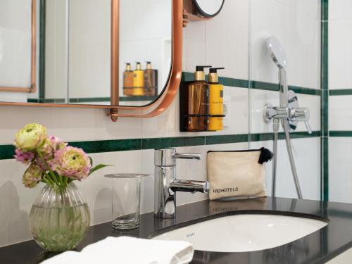 a bathroom with a sink and a vase with flowers at H10 Cubik 4* Sup in Barcelona