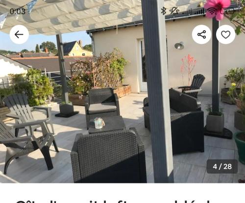 a patio with chairs and tables and an umbrella at L 'esprit Loft in Montreuil-sur-Maine