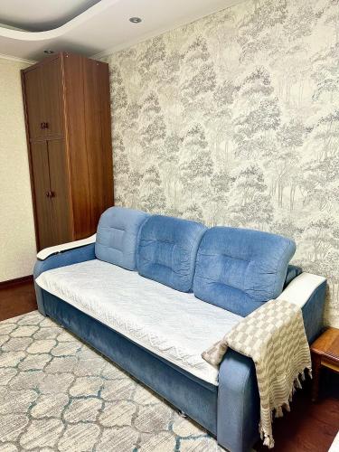 un divano blu in una stanza con un muro di Апартаменты аэропорт a Almaty