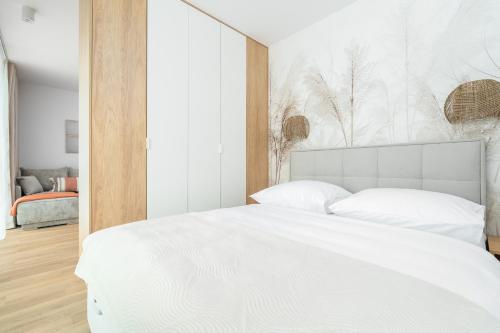 a bedroom with a white bed with a white headboard at Sarbinove City Apartments in Sarbinowo