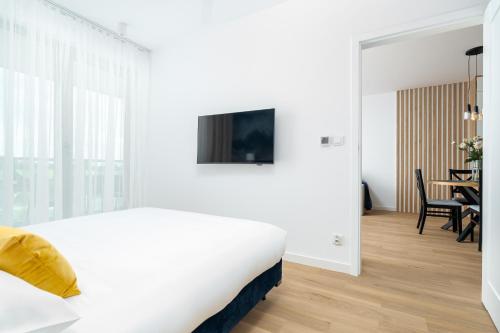 a white bedroom with a bed and a dining room at Sarbinove City Apartments in Sarbinowo