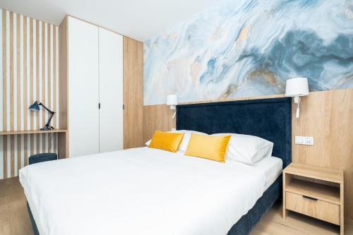 a bedroom with a bed and a painting on the wall at Sarbinove City Apartments in Sarbinowo