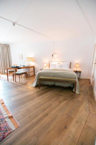 a white bedroom with a bed and a wooden floor at Louis Hotel in Munich