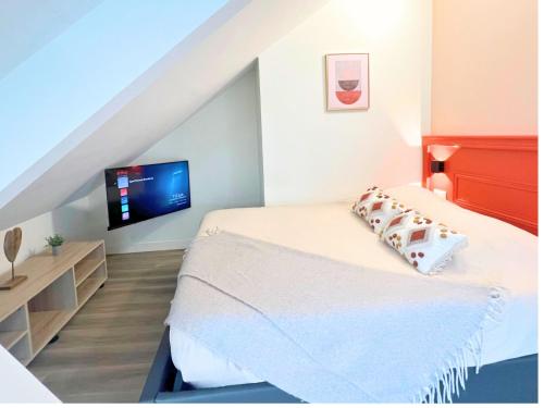 Un dormitorio con una cama con un televisor en la pared. en Studio spacieux et élégant au cœur de Bourbourg - gare à proximité, en Bourbourg