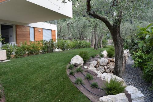 a garden with rocks and a tree in a yard at "CASABANA" - relax tutto l'anno - giardino - piscina Top in Malcesine