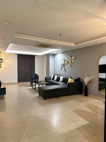 a living room with a black couch and a table at Luxury Apartments at Goldcrest Mall and Residency DHA Phase 4 by Nirvana Nests in Lahore