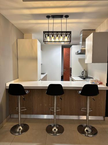 a kitchen with two bar stools at a counter at Luxury Apartments at Goldcrest Mall and Residency DHA Phase 4 by Nirvana Nests in Lahore